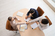© Pixel-Shot - Female business mediator with clients shaking hands at table in office, top view