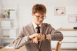 © Pixel-Shot - Young redhead businessman looking at wristwatch in office
