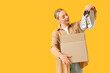 © Pixel-Shot - Young woman with parcel box and new sneakers on yellow background