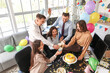 © Pixel-Shot - Group of young business people with drinks celebrating Birthday at party in office