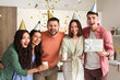 © Pixel-Shot - Group of young friends with drinks and gift celebrating Birthday at party in kitchen