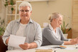 © Pixel-Shot - Senior couple with refund form at table in room