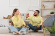 © Pixel-Shot - Young couple with tools and posters giving each other high-five on floor at home