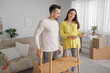 © Pixel-Shot - Happy pregnant couple with manual assembling shelving unit at home