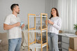 © Pixel-Shot - Happy couple with cups of coffee after assembling shelf unit at home