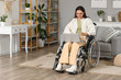 © Pixel-Shot - Young woman in wheelchair using laptop at home