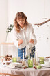© Pixel-Shot - Beautiful young woman decorating table for Thanksgiving Day dinner with pumpkins and candles in dining room