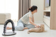 © Jirawatfoto - Happy asian woman using brush on friendly pet cat on floor at comfortable home improving mental health and everyday wellness during relaxing indoor activity for animal companion