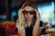 © nicoletaionescu - Woman Wearing Sunglasses Looking Sad and Stressed in Restaurant. Person hiding behind dark shades feeling depressed and overwhelmed