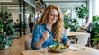© Elif - Smiling businesswoman eating a healthy salad during lunch break in modern office.