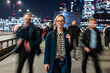 © Westend61 - Woman waiting on busy London bridge at night
