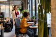 © BusinessClass by W61 - Businesswoman working at modern office desk while colleague stands nearby