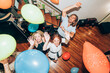 © Westend61 - Male and female friends dancing with colorful balloons during party at home
