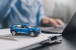 © Anon - Car insurance and loan approval concept. A miniature car placed on insurance contract document policy agreement. vehicle finance, policy management, rental, sales, and claims service.