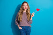 © deagreez - Young woman with red heart wand smiling against blue background