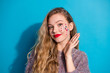 © deagreez - Young stylish woman with glitter makeup posing with hand on blue background wearing a cozy sweater fashion forward and friendly mood