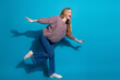 © deagreez - Young woman in casual sweater jeans and sneakers jumps with joy against blue background