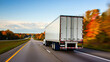 © design goodie - A white semi-truck speeds down an open highway bordered by vibrant autumn trees, symbolizing efficient freight transportation.