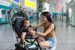 © leungchopan - Mother securing baby in stroller at station