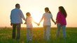 © Victoriia - Dad mom, daughters, outdoor picnic. Parents, dad mom, children enjoy walk in nature. Family vacation on lawn. Family unity. Happy family, dad mom, daughters are walking through summer park at sunset.