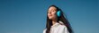 © Andrii Zastrozhnov - Asian female young adult with turquoise headphones outdoors under clear blue sky enjoying music and relaxation eyes closed serene portrait wellness moment