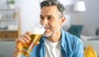 © Indri - A mature man enjoying a refreshing glass of beer indoors, set in a bright, modern living room environment