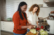 © Jelena - Diverse women cooking healthy food together in kitchen