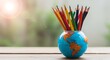 © KABIR - Colorful pencils in a globe-shaped holder on a wooden desk, symbolizing global education and creativity