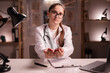 © Andrii Lysenko - Portrait of female doctor or medical student intern with stethoscope asking help holding palms up sitting at office desk looking at camera working during night shift at hospital