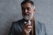 © opolja - Confident mature businessman chilling relaxing drinking enjoying whiskey against grey wall.