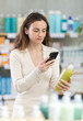 © JackF - Woman in summer clothes scans code on medicinal shampoo to check the expiration date
