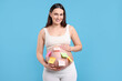 © New Africa - Pregnant woman with notes with different names on her belly against light blue background