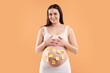 © New Africa - Pregnant woman with notes with different names on her belly against orange background