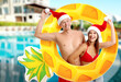 © New Africa - Happy couple with Santa hats and inflatable ring against swimming pool at sea resort