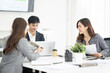 © BTM_Graphic - Asian business team discussing documents during a meeting in modern office.