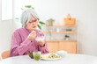© buritora - A gray-haired senior woman eating in the dining room at home