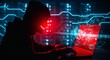 © Graphics River - Shadowy figure in a hoodie intensely focused on a glowing red laptop screen, symbolizing cybercrime, data breach, and digital security threats within a complex network environment
