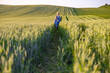 © sofiko14 - A mother and child stroll through a lush green wheat field under a clear sky, enjoying a peaceful moment together