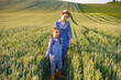 © sofiko14 - A woman and a young girl walk through a golden wheat field under a clear sky, enjoying a sunny day outdoors