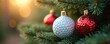 © Maryna - Christmas tree branches hold festive ornaments. One ball resembles a golf ball, others are red and glittery. Soft light glows in background bokeh creating a holiday mood.