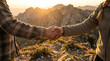 © Rohan Katwe - Two hikers shake hands on a rocky mountain ridge at sunset, symbolizing teamwork, trust and accomplishment after an adventurous hike in the wilderness surrounded by dramatic landscape light.