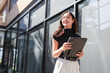 © crizzystudio - Young woman holding tablet computer smiling outdoors