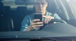 © Eve - Young man using a smartphone while driving a car. Concept of dangerous driving, distracted driver, traffic violation, mobile phone addiction, and road safety risk.