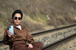 © Mandy - Woman holding smartphone sitting on railroad tracks traveling