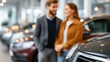 © Denis Yevtekhov - Sleek pre-owned sedan gleaming under showroom lights, faceless couple in background discussing with a salesperson, defocused other vehicles behind, second hand car dealership, used