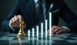 © Rhony - A businessman holding a golden king chess piece with a rising growth graph overlay, symbolizing strategic leadership and financial success.
