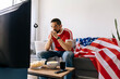 © kleberpicui - American sports fan watching game on television at home