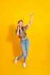 © deagreez - Young woman dancing with headphones against bright yellow background wearing floral top and jeans for lifestyle fashion and music vibe