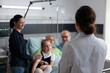 © DC Studio - Nurse practitioner visiting happy elderly patient room in recovery. Sick grandmother smiling family chatting with unidentified female geriatric professional doctor at medical clinic room.