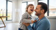 © Marin Studio - A happy father holding his laughing little daughter in a bright modern living room with large windows